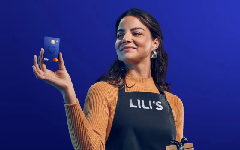A small business owner holding a blue Tide business Mastercard
